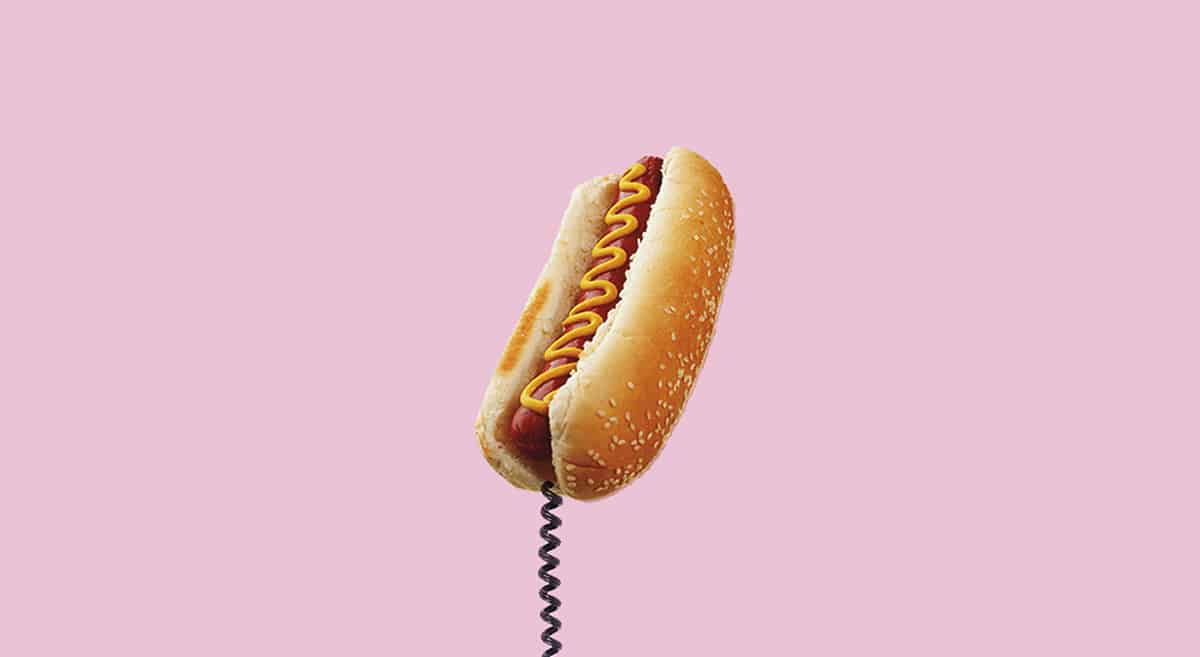 Lyserød baggrund med hotdog som telefonrør